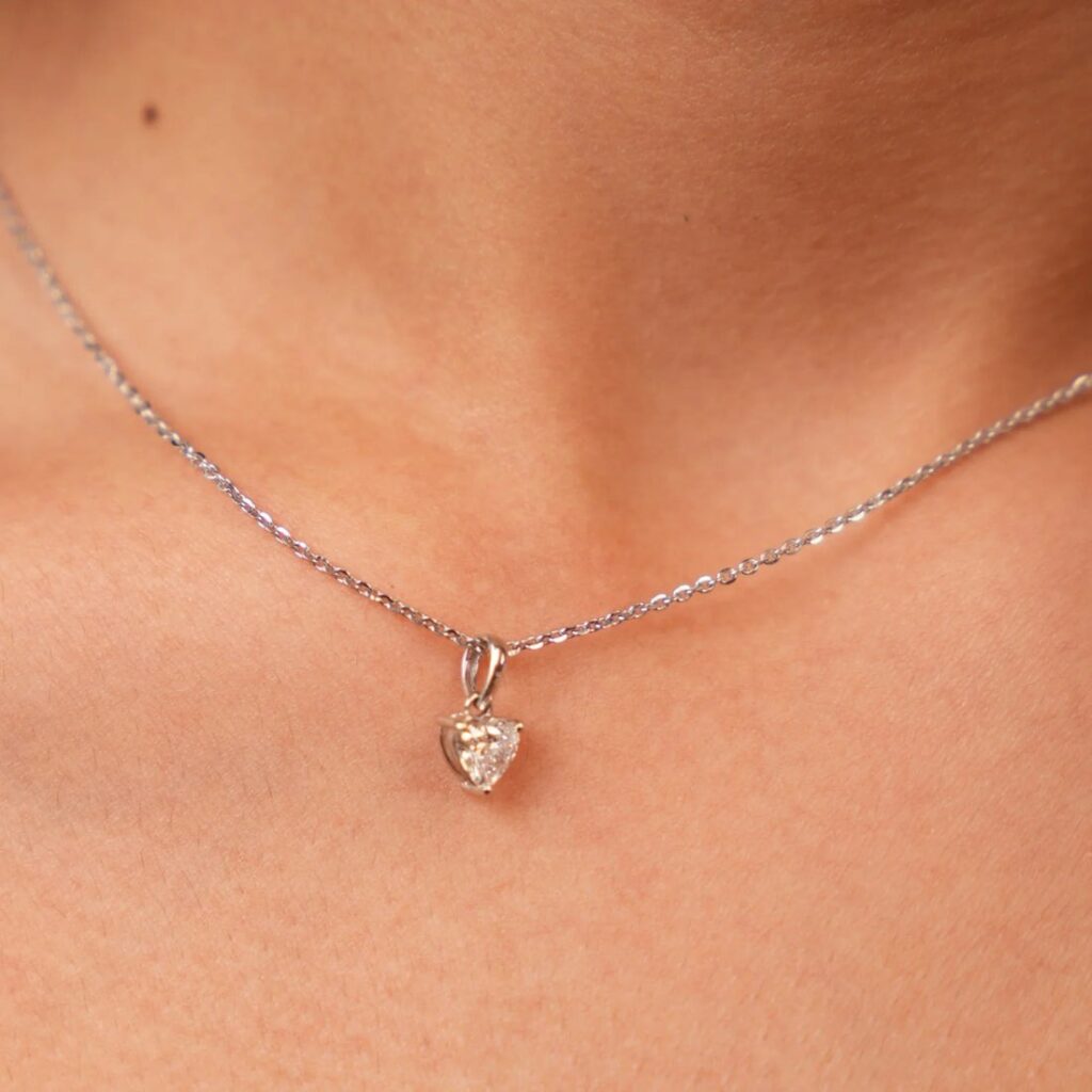 Elegant silver necklace with heart-shaped diamond pendant on neckline
